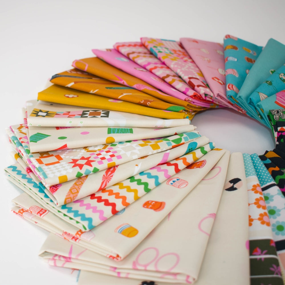 A circular arrangement of colorful sewing notion themed patterned fabric swatches on a white background, showing many different prints and colors including pink, teal, green, orange, black, and white.
