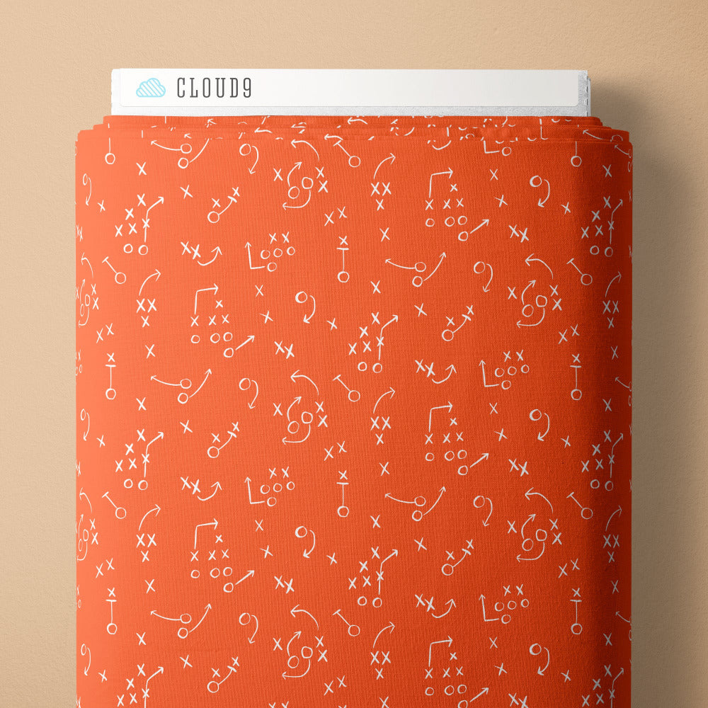 White football play diagrams on an orange fabric background