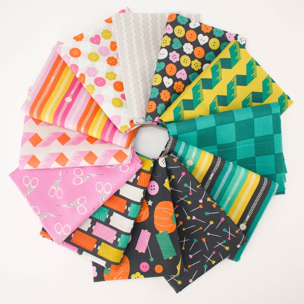 A stack of folded fabric pieces in various colorful sewing themed patterns, including pink, orange, green, black, and white, arranged neatly on a white background.