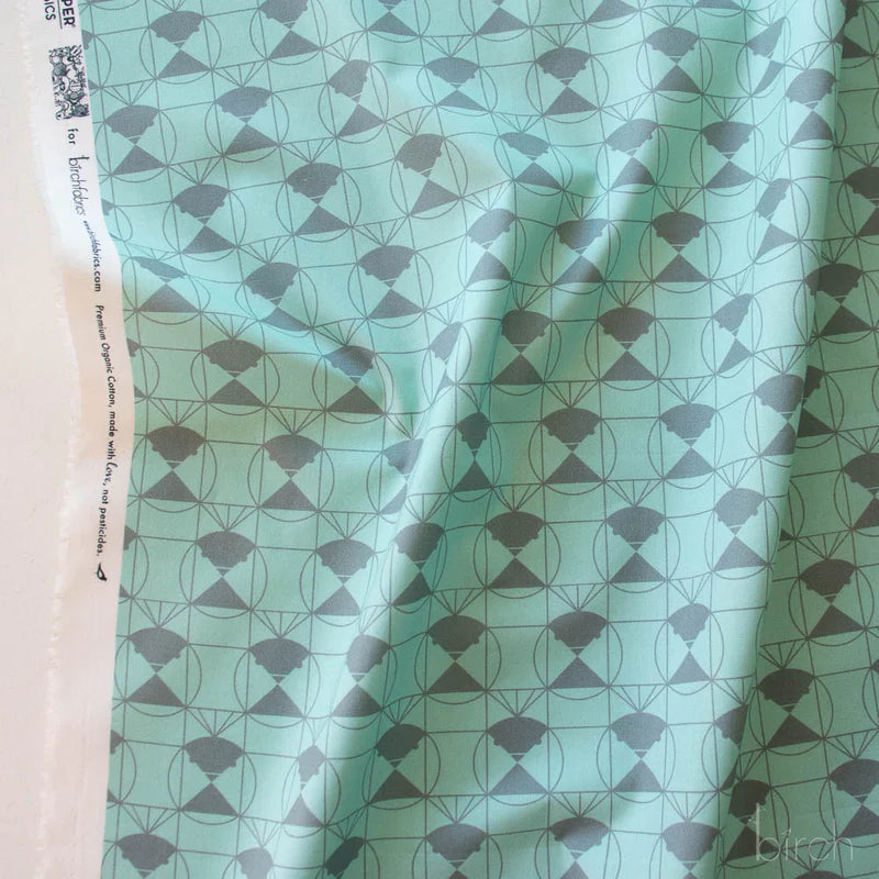Patterned fabric with a gray green geometric design on a lighter green background