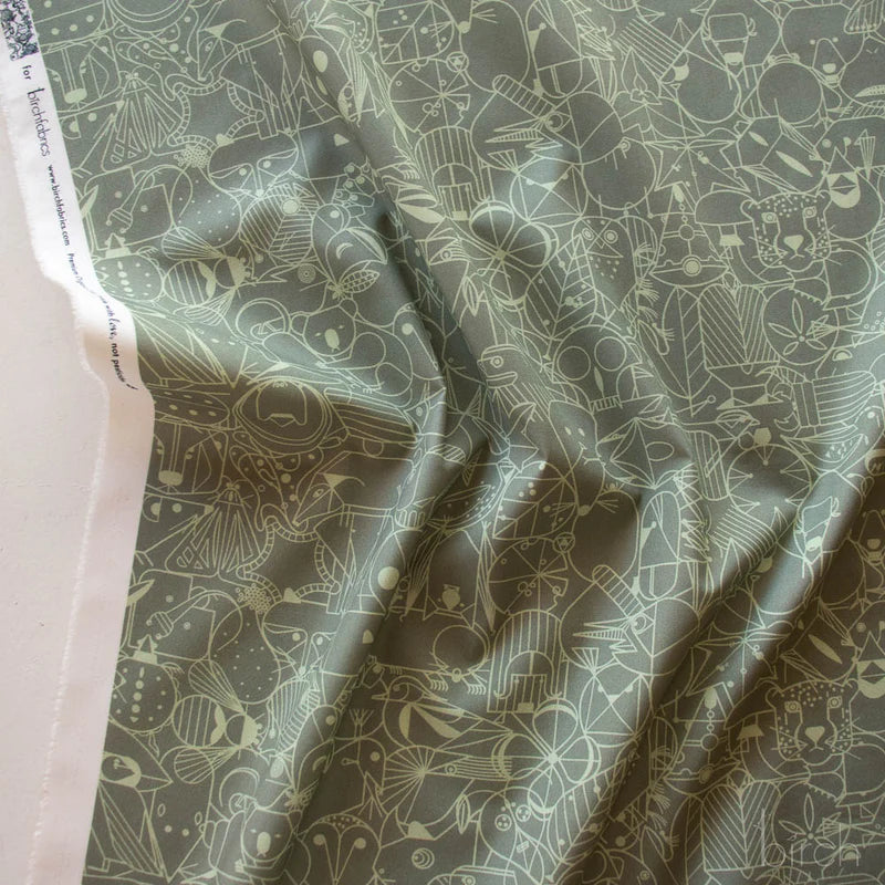 Patterned fabric with geometric animal illustrations in green on a medium green background