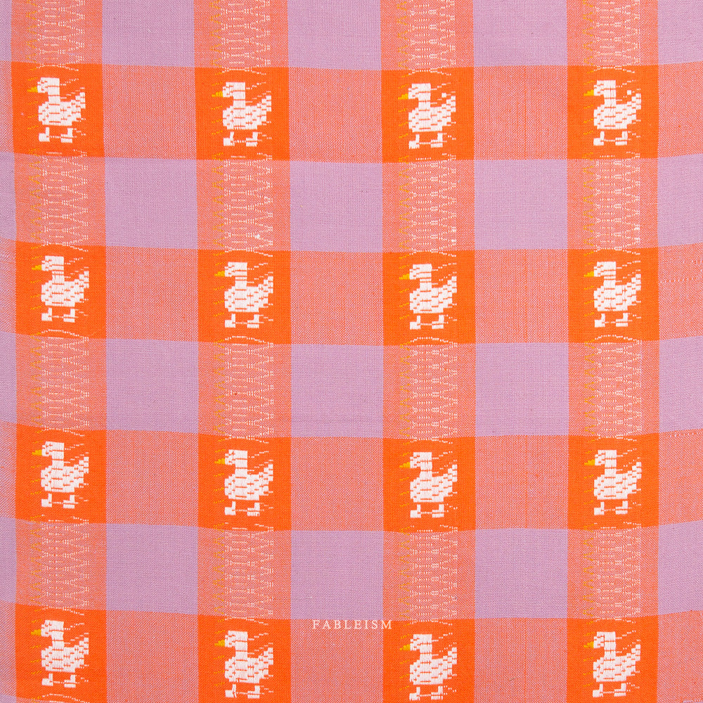 Checkered fabric with orange and purple squares and white ducks on a white background