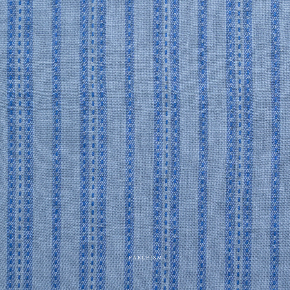 Close-up of blue striped fabric with 'Fableism' branding.