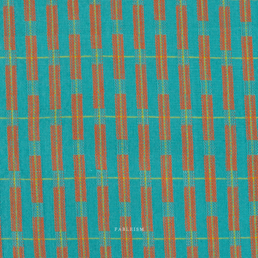 Teal fabric with red and yellow pattern on a textured surface