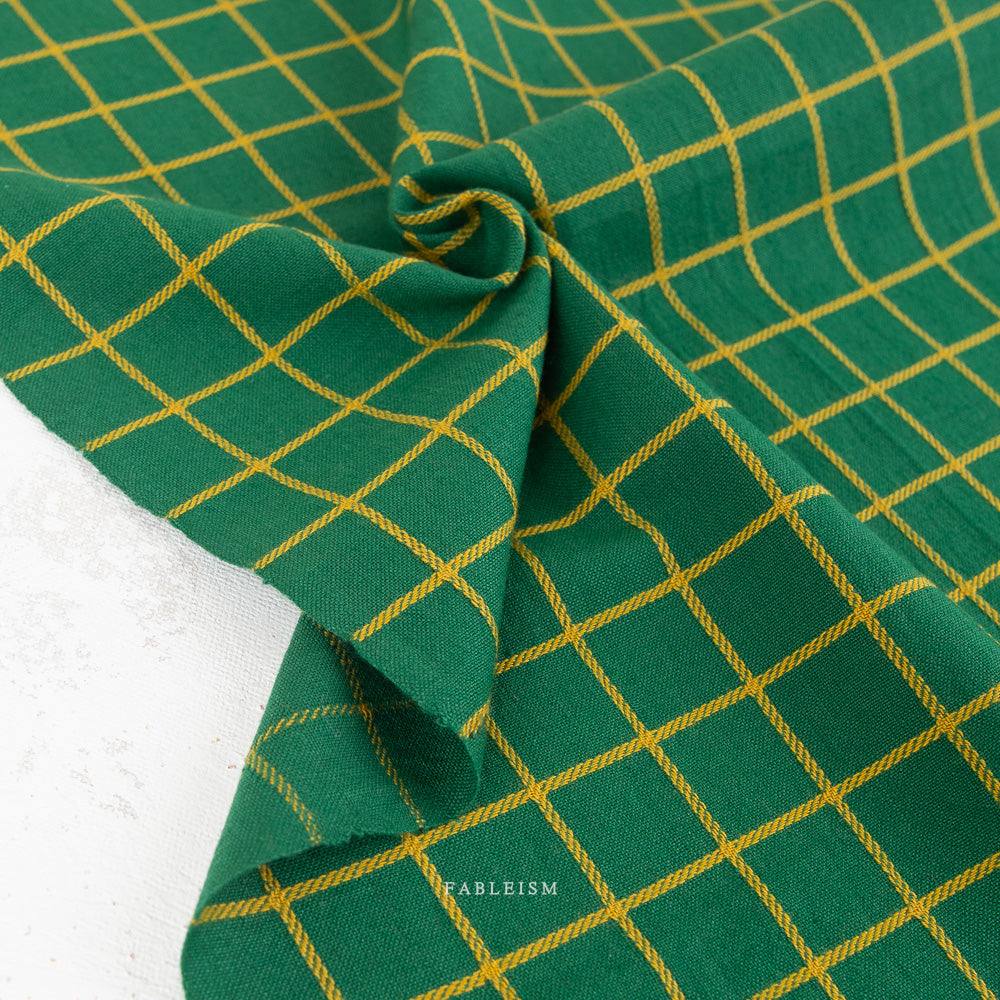 Green fabric with a yellow grid pattern, draped to show its texture and weave.