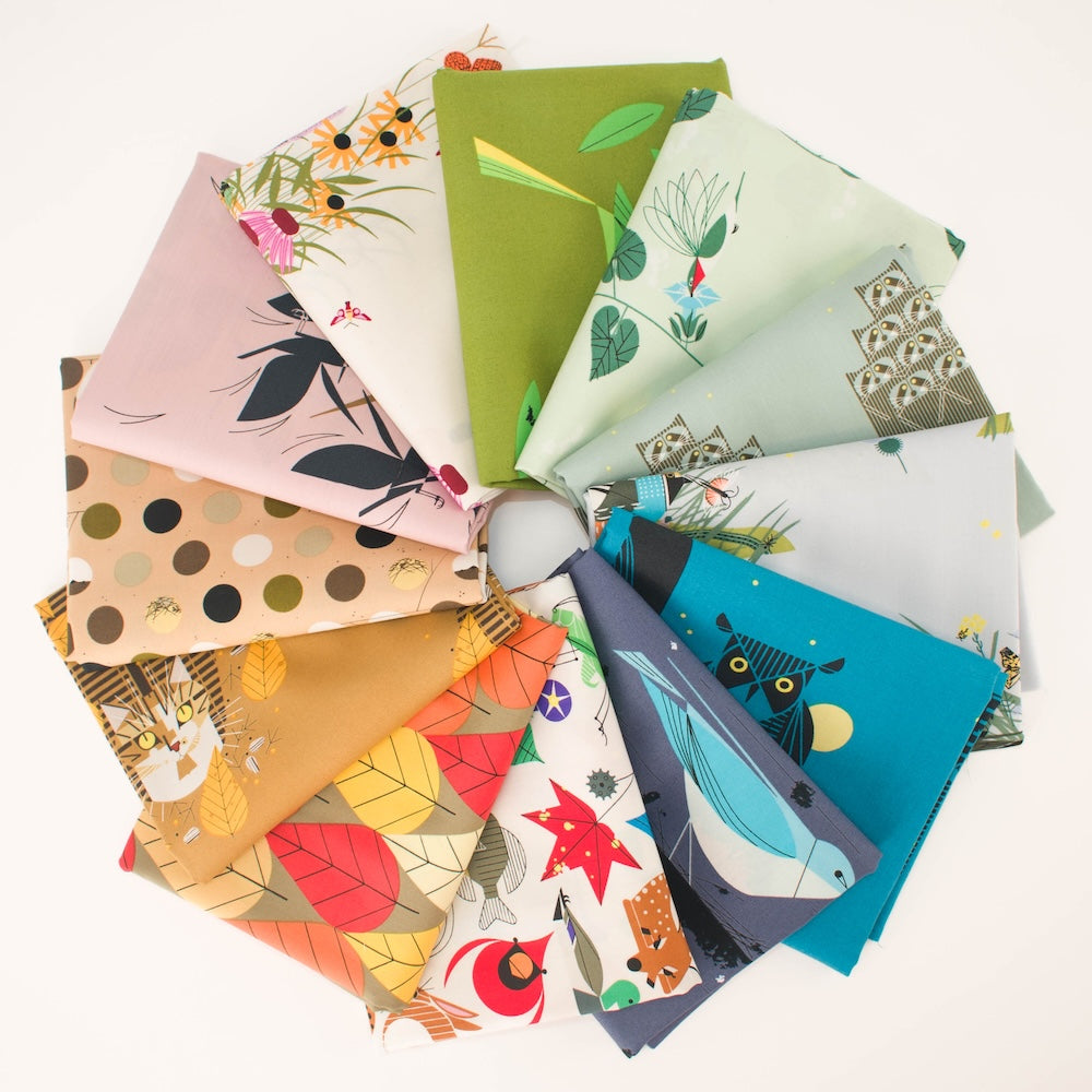 A stack of folded patterned fabric pieces in various colors and designs, including botanical leaf prints, polka dots, and floral motifs, photographed on a clean white background.