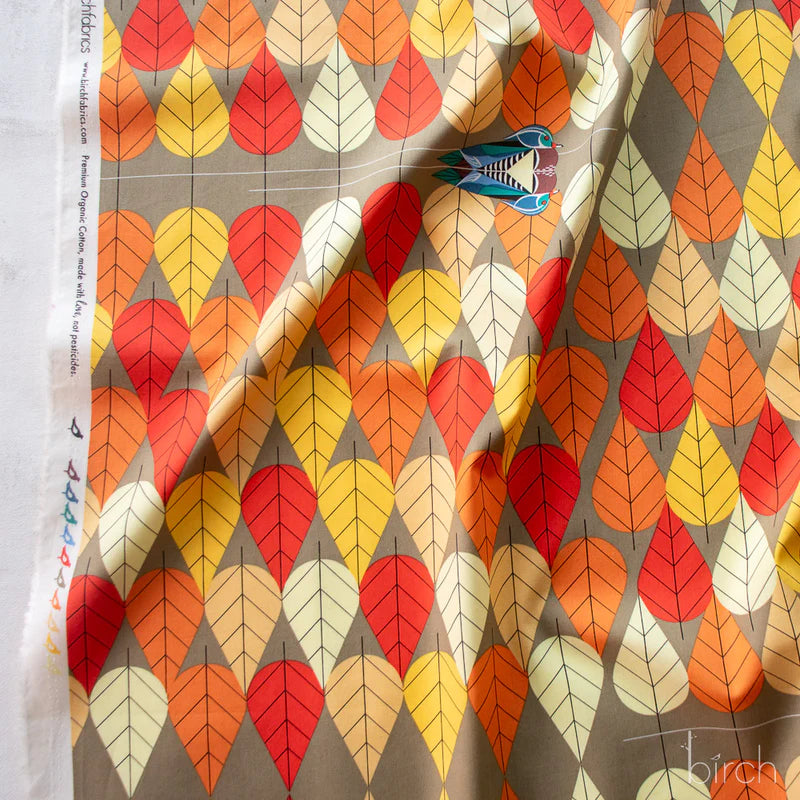 Patterned fabric with colorful autumnal leaf/tree design on a gray background, with an occasional swimming duck.