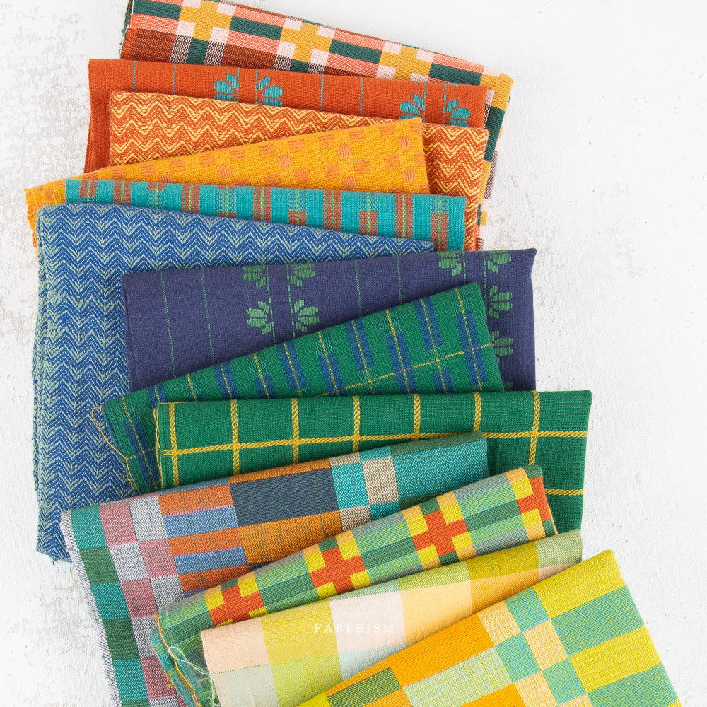 A stack of folded colorful patterned fabrics on a clean white background.